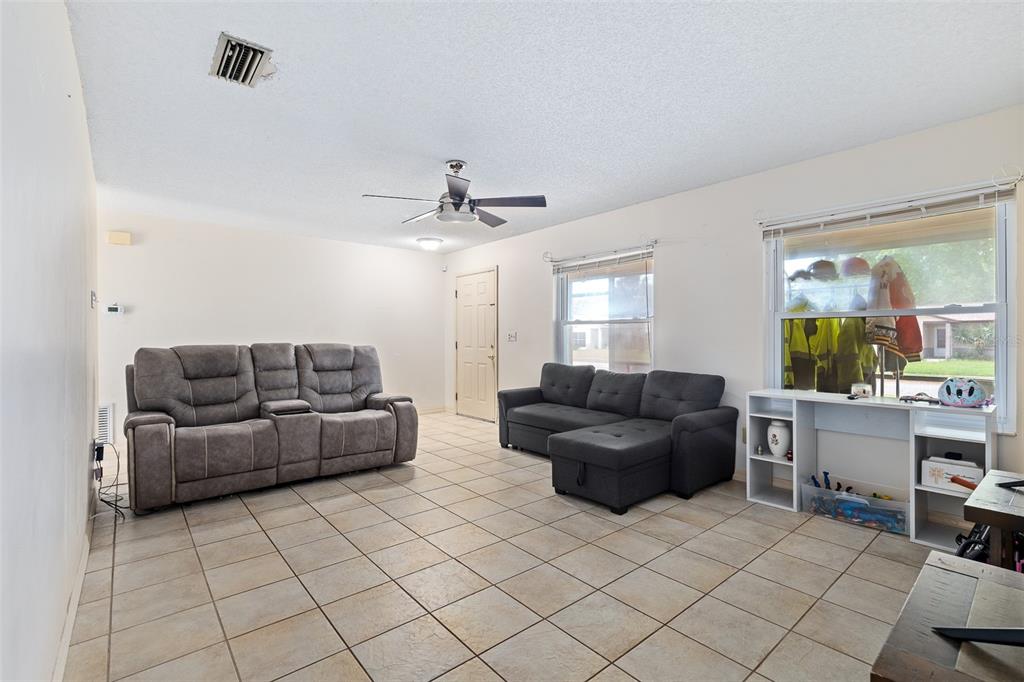 A kitchen features oak cabinets, a black stove, tile flooring, and a small dining area — 1218 MELLISA DRIVE, PORT ORANGE, FL