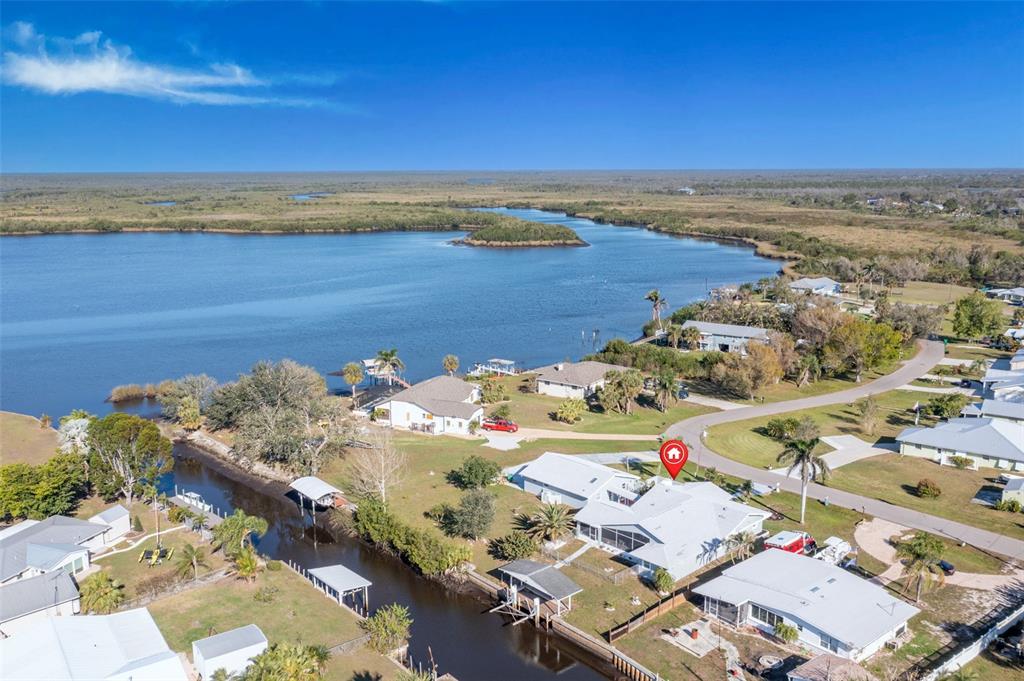 An aerial view shows a waterfront house with a canal, boat docks, and nearby lake — 541 RIDGECREST DRIVE, PUNTA GORDA, FL