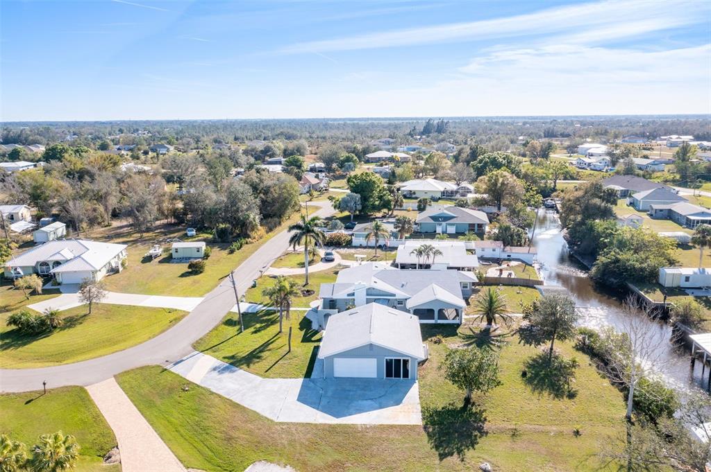 An aerial view shows a light blue house with a garage and a canal nearby — 541 RIDGECREST DRIVE, PUNTA GORDA, FL