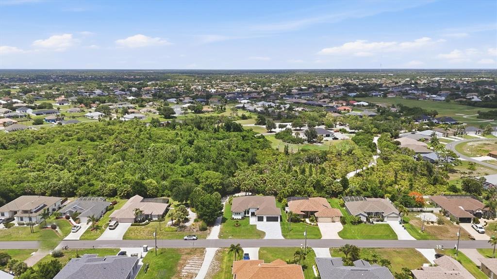 An aerial view shows a suburban neighborhood with houses bordering a large area of vegetation — 166 MEDALIST ROAD, ROTONDA WEST, FL