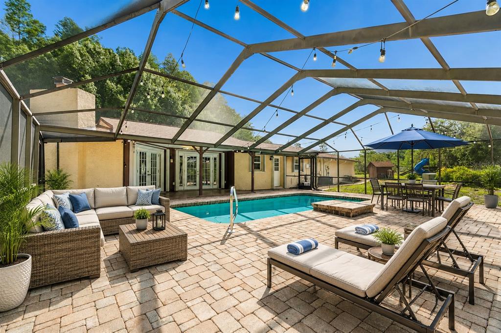A screened-in patio features a swimming pool, lounge furniture, and a dining area — 7635 TANGLEWOOD DRIVE, NEW PORT RICHEY, FL