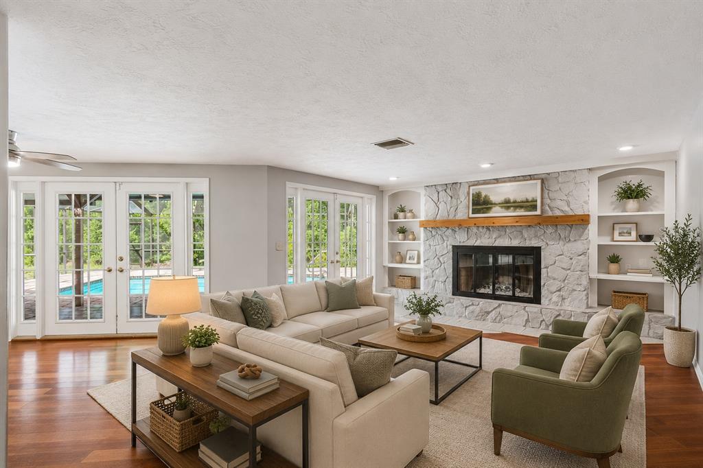 A living room features a white stone fireplace, cream sofa, green armchairs, and glass doors — 7635 TANGLEWOOD DRIVE, NEW PORT RICHEY, FL