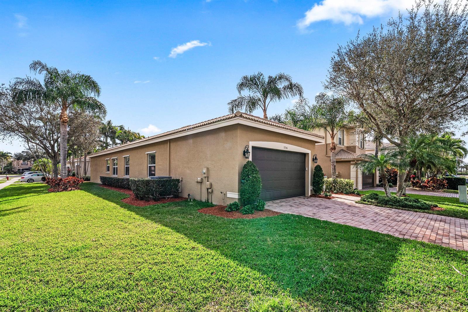 A tan stucco house features a dark garage door and a brick paver driveway — 11546 Ponywalk Trail, Boynton Beach FL 33473, BOYNTON BEACH, FL