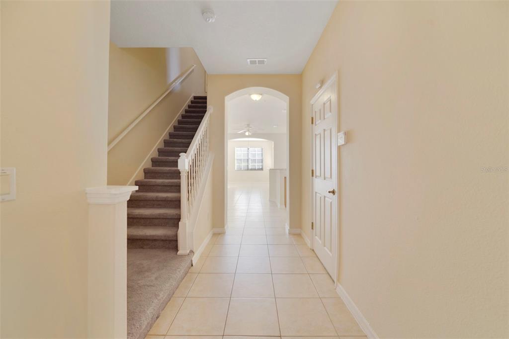 A tiled entryway features a carpeted staircase with a white railing and an arched doorway — 851 ASSEMBLY COURT, KISSIMMEE, FL