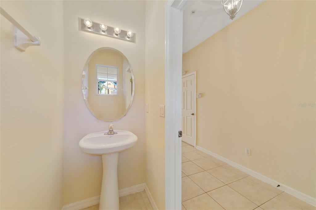 A small powder room features a pedestal sink, an oval mirror, and a vanity light — 851 ASSEMBLY COURT, KISSIMMEE, FL