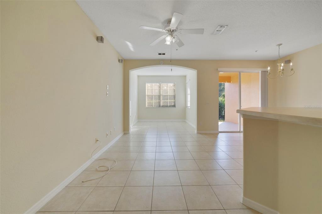 An empty living area with tile flooring, a ceiling fan, and a sliding glass door — 851 ASSEMBLY COURT, KISSIMMEE, FL