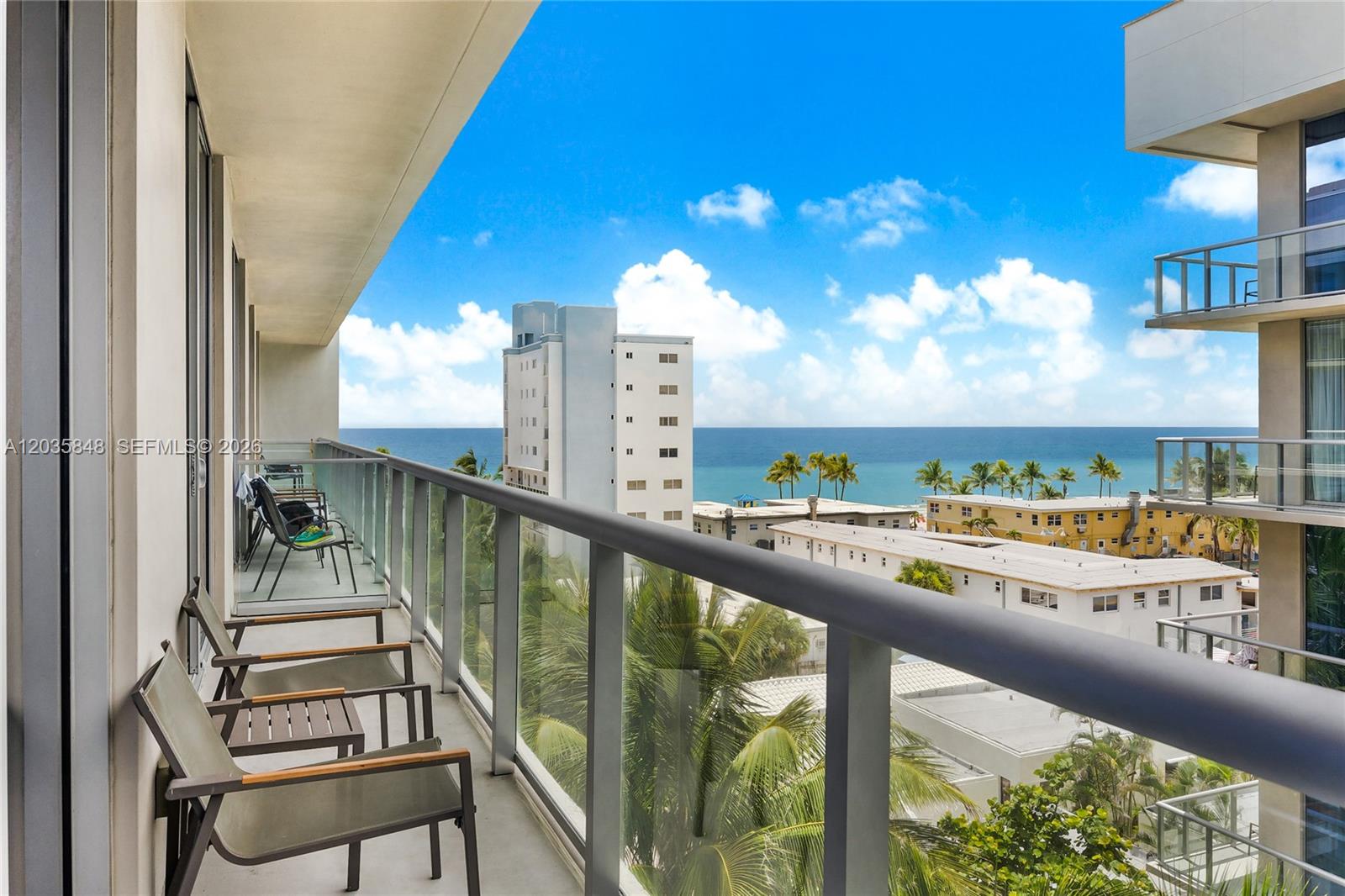 A balcony with outdoor seating overlooks the ocean and surrounding buildings under a blue sky — 777 N Ocean Dr # N516, Hollywood FL 33019, HOLLYWOOD, FL