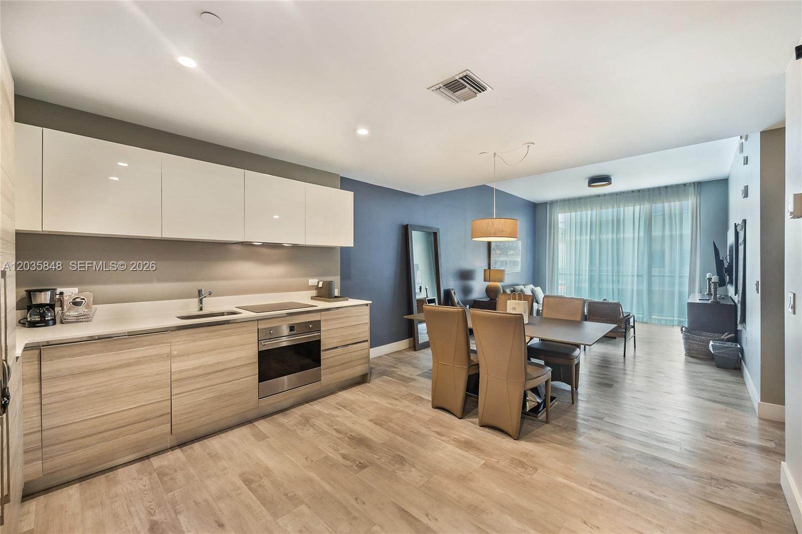A modern kitchen with light wood cabinets and white upper cabinets opens to a dining area — 777 N Ocean Dr # N516, Hollywood FL 33019, HOLLYWOOD, FL
