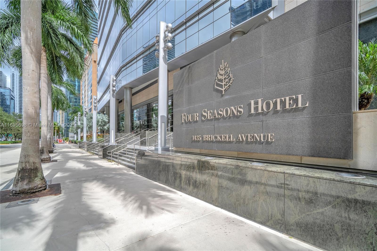 The exterior of a modern glass building features a large stone sign for a hotel — 1435 Brickell Ave # 3012, Miami FL 33131, MIAMI, FL