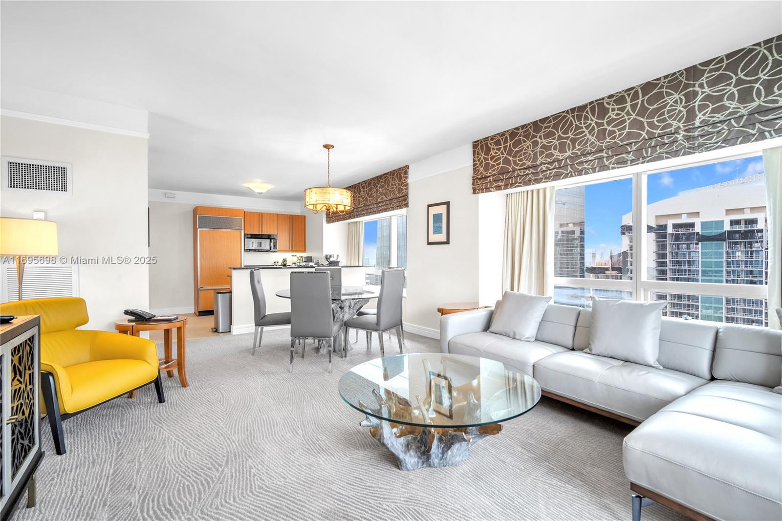 A living and dining area features a yellow armchair, grey sofa, and glass-topped coffee table — 1435 Brickell Ave # 3012, Miami FL 33131, MIAMI, FL