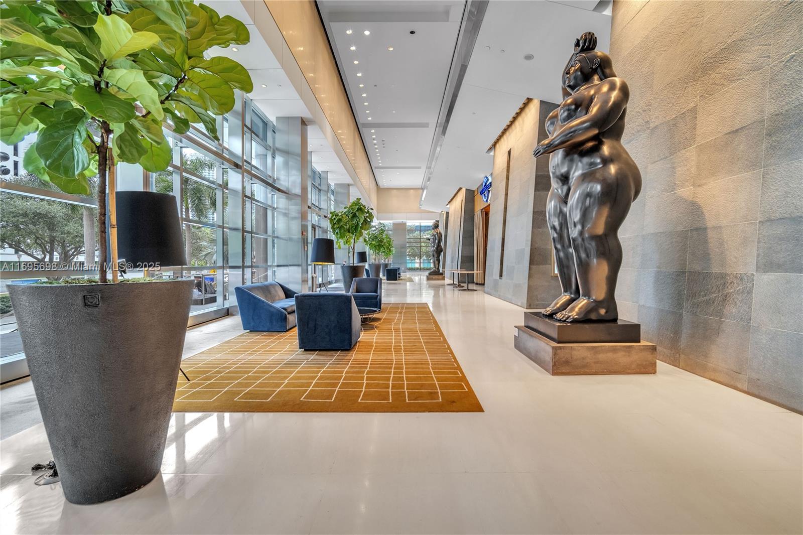 A modern lobby features a large bronze sculpture, blue seating, and a patterned area rug — 1435 Brickell Ave # 3012, Miami FL 33131, MIAMI, FL