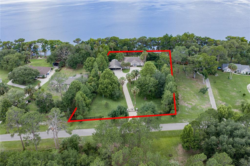 An aerial view shows a house with a long driveway surrounded by trees and water — 14014 SE 201ST TERRACE, HAWTHORNE, FL