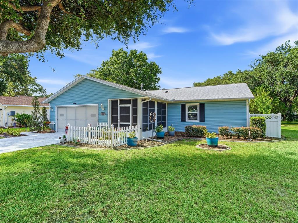 A light blue single-story house with a white picket fence and a screened-in front porch — 2107 GREENLAW COURT, LEESBURG, FL