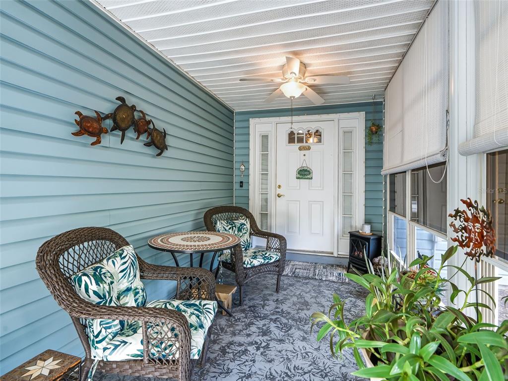 A covered porch features blue siding, wicker furniture, a ceiling fan, and a front door — 2107 GREENLAW COURT, LEESBURG, FL