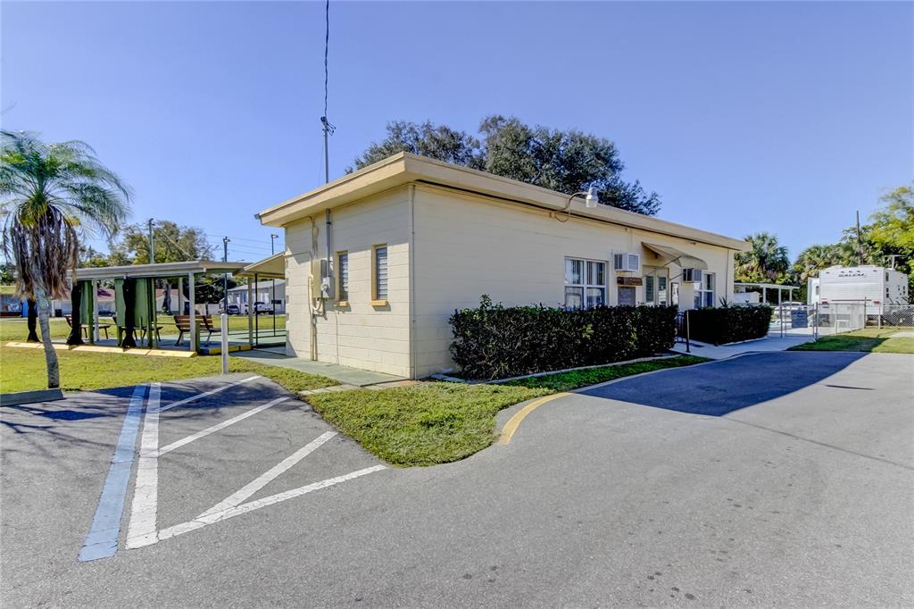 A single-story beige building with a flat roof stands next to a paved parking area — 4677 66TH LANE N UNIT 1, ST PETERSBURG, FL