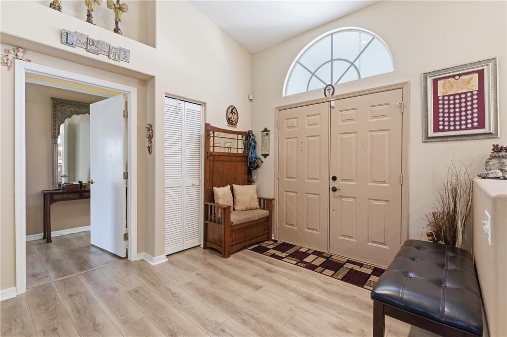 A bright entryway features light wood-look flooring, double front doors, and a wooden hall tree — 14247 TEASDALE AVENUE, HUDSON, FL