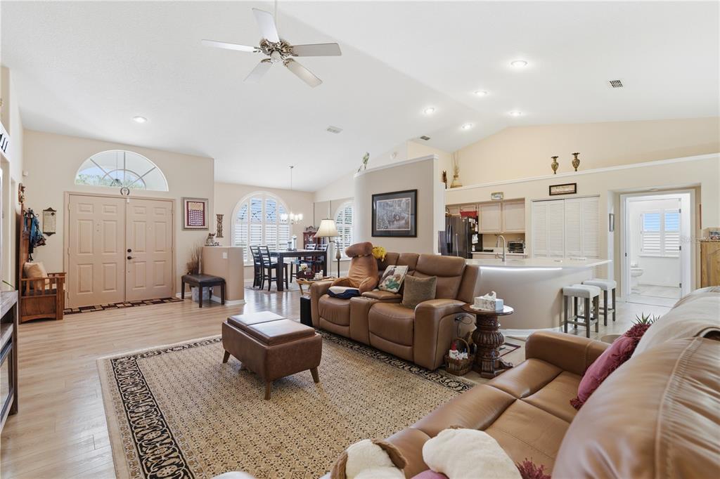 A living room with light wood flooring, a brown leather sofa, and an open kitchen — 14247 TEASDALE AVENUE, HUDSON, FL