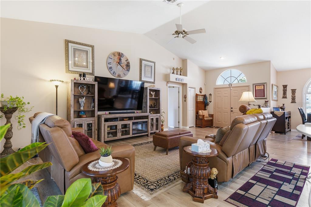A living room features leather furniture, a large television, and a vaulted ceiling — 14247 TEASDALE AVENUE, HUDSON, FL