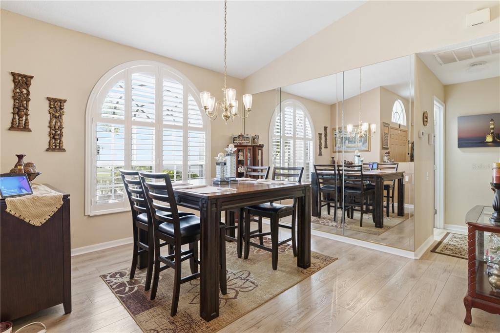 A dining room features a dark wood table, chairs, a chandelier, and a mirrored wall — 14247 TEASDALE AVENUE, HUDSON, FL