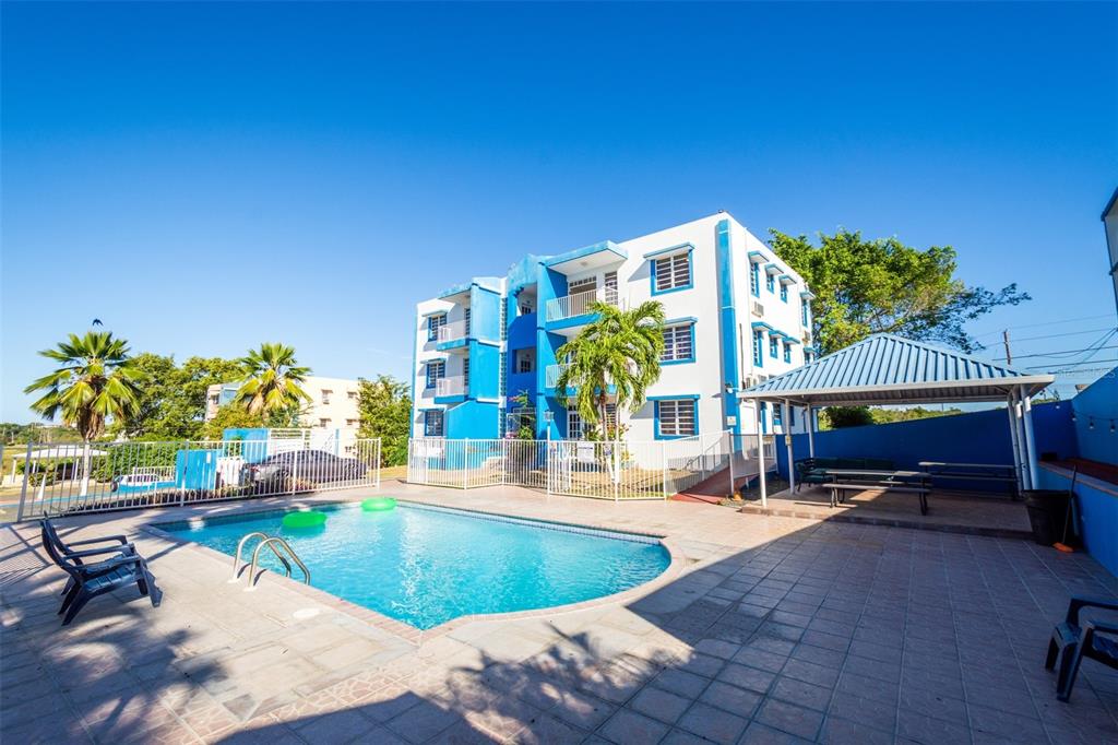 A blue and white apartment building stands behind a swimming pool and a covered patio — ST 307 KM 7.4, BOQUERON, PR