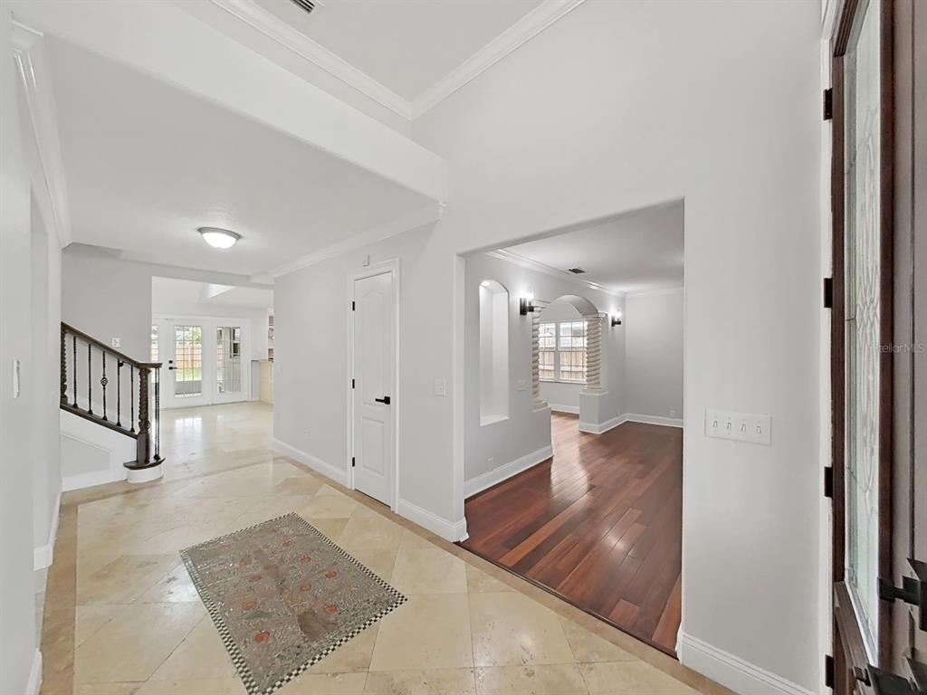 An entryway with tile flooring, a staircase, and an arched opening to a wood-floored room — 3322 SCHEFFLERA ROAD, TAMPA, FL