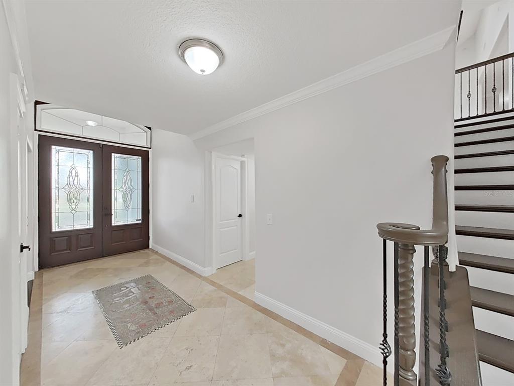A foyer with tile flooring, a staircase, and a double front door with glass inserts — 3322 SCHEFFLERA ROAD, TAMPA, FL