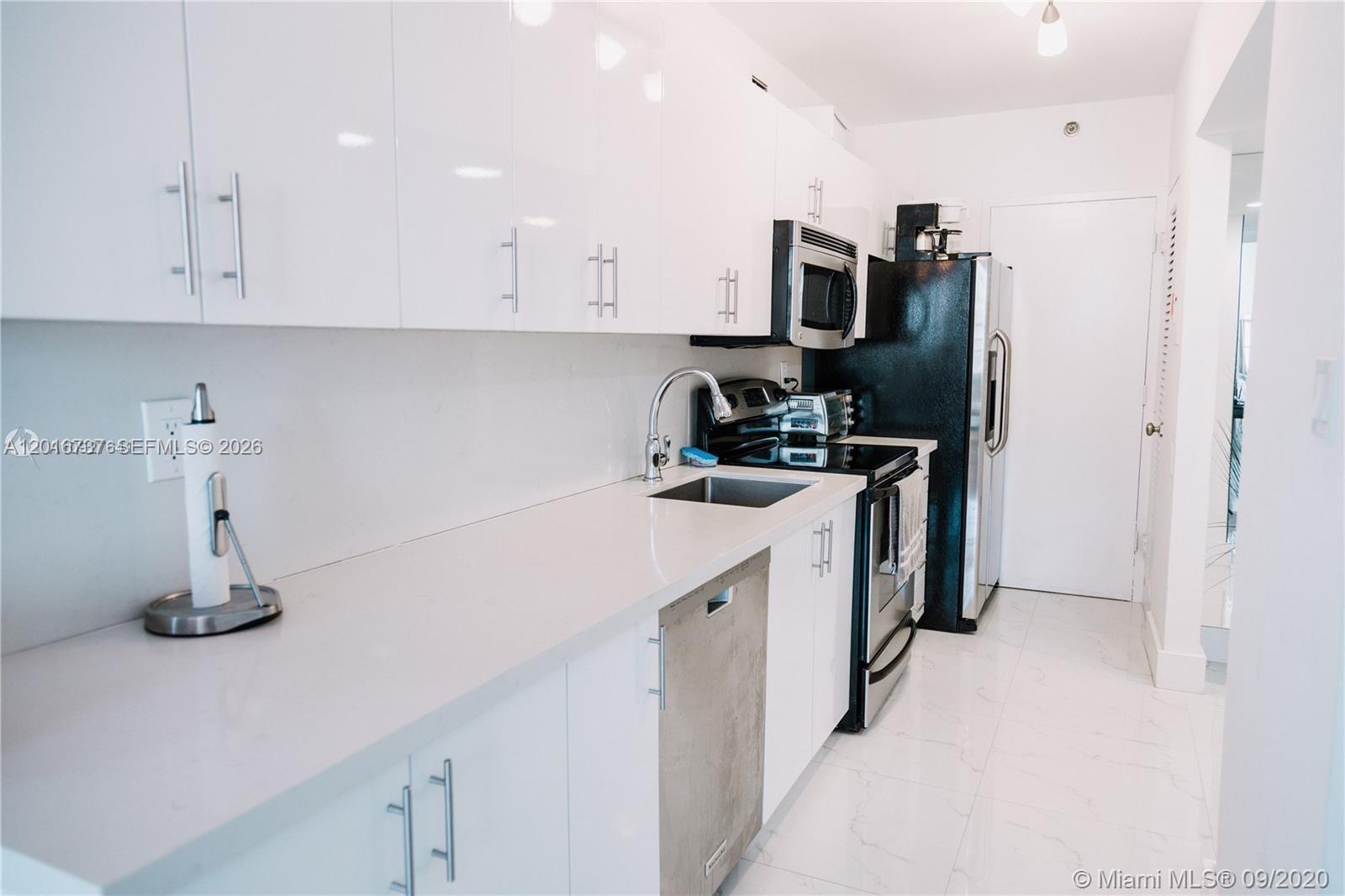 A modern kitchen features white cabinets, stainless steel appliances, and white countertops — 100 Lincoln Rd # 1526, Miami Beach FL 33139, MIAMI BEACH, FL