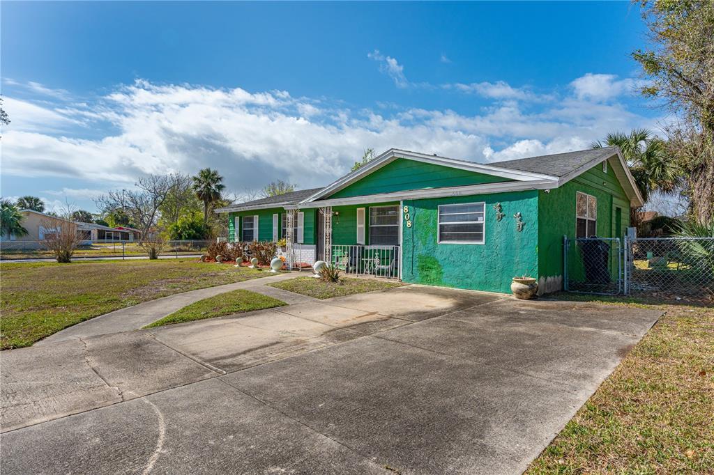 A kitchen features wood cabinets, a stainless steel refrigerator, and a view into the dining room — 808 KATHY STREET, DAYTONA BEACH, FL