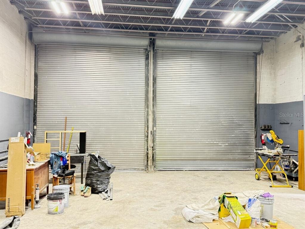 An industrial warehouse space features two large metal roll-up doors and concrete flooring — 14041 NW 20TH AVENUE, OPA LOCKA, FL