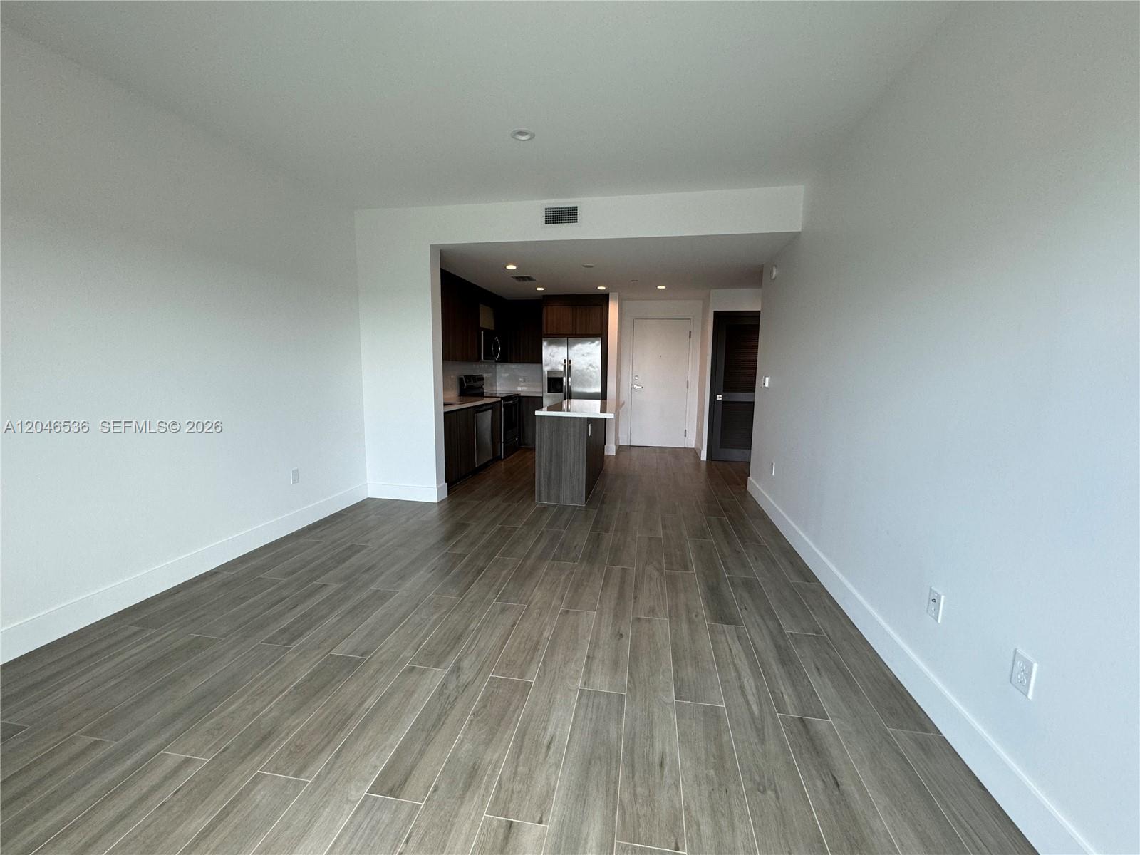 An open-concept living area features wood-look tile flooring and an adjacent kitchen with dark cabinetry — 1938 Jackson St # 503, Hollywood FL 33020, HOLLYWOOD, FL