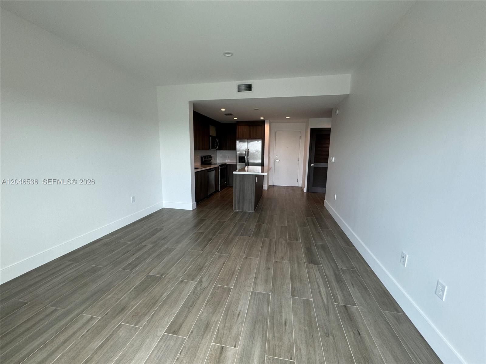An open-concept living area features wood-look tile flooring and a kitchen with dark cabinetry — 1938 Jackson St # 503, Hollywood FL 33020, HOLLYWOOD, FL