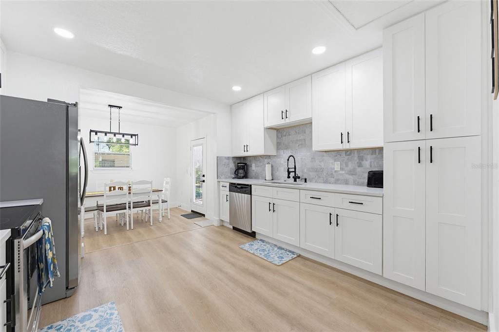A kitchen with white cabinets, stainless steel appliances, and light wood-look flooring — 1275 PALM STREET, CLEARWATER, FL