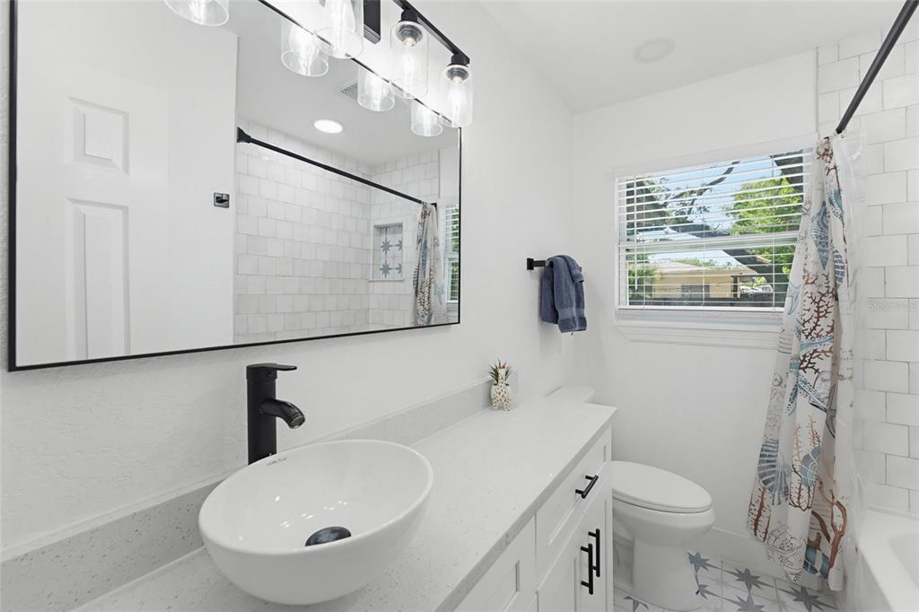 A modern bathroom features a white vanity with a vessel sink, mirror, and shower — 1275 PALM STREET, CLEARWATER, FL
