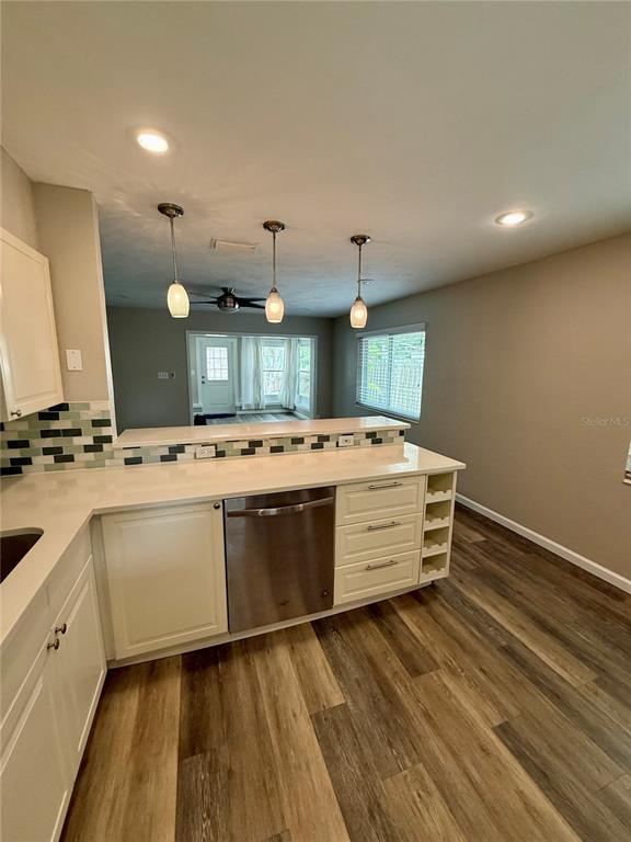 A kitchen features white cabinets, a stainless steel dishwasher, and a tiled backsplash — 2716 BLOSSOM DRIVE, SARASOTA, FL