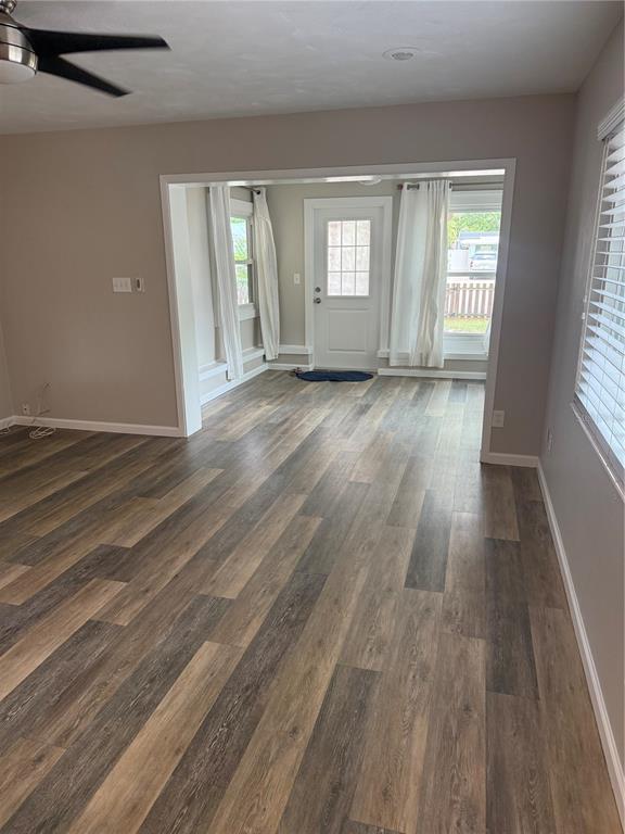 A living room with wood-look vinyl flooring leads into a sunroom with a back door — 2716 BLOSSOM DRIVE, SARASOTA, FL