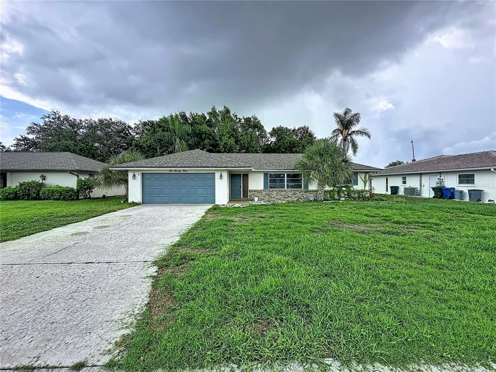 A single-story house with a blue garage door, stone facade, and a concrete driveway — 1093 N CYPRESS POINT DRIVE, VENICE, FL