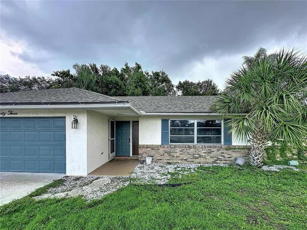 A single-story house with a brick facade, a blue front door, and a palm tree — 1093 N CYPRESS POINT DRIVE, VENICE, FL