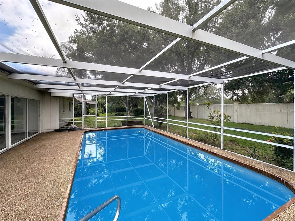 A rectangular swimming pool is enclosed by a screened lanai with a concrete deck — 1093 N CYPRESS POINT DRIVE, VENICE, FL
