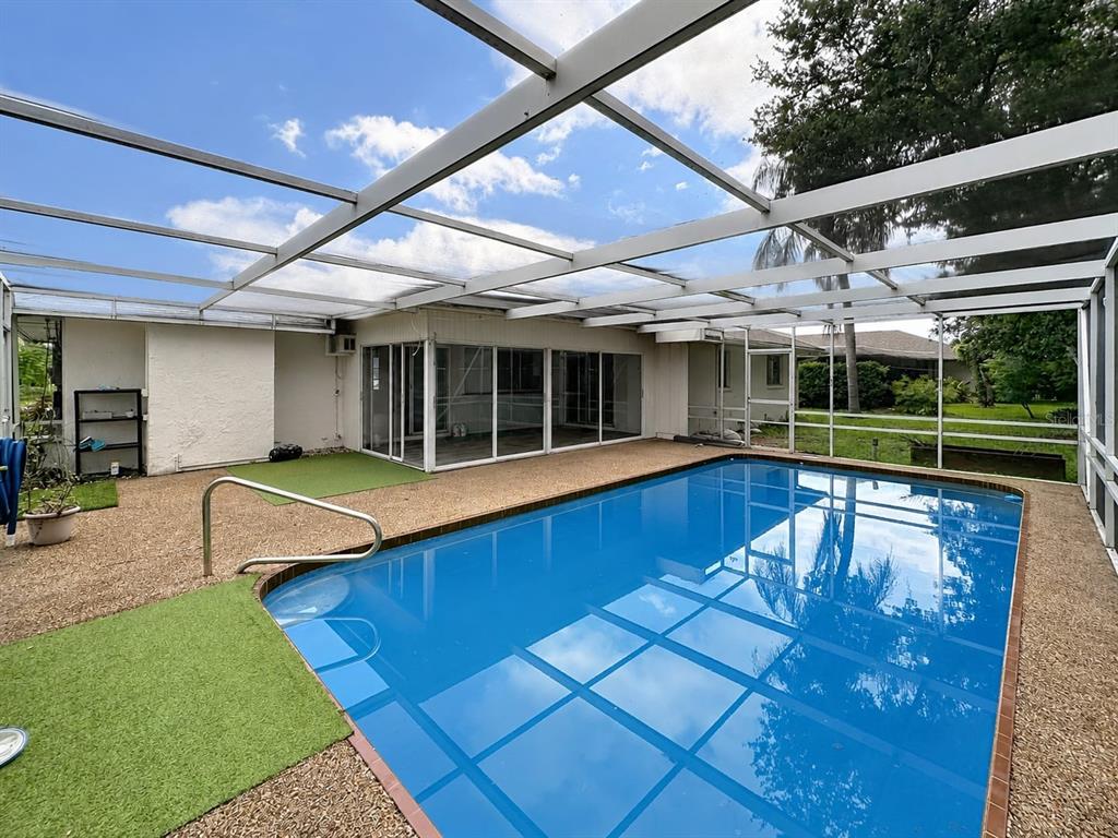 A screened-in swimming pool with a gravel deck and artificial turf patches next to a house — 1093 N CYPRESS POINT DRIVE, VENICE, FL