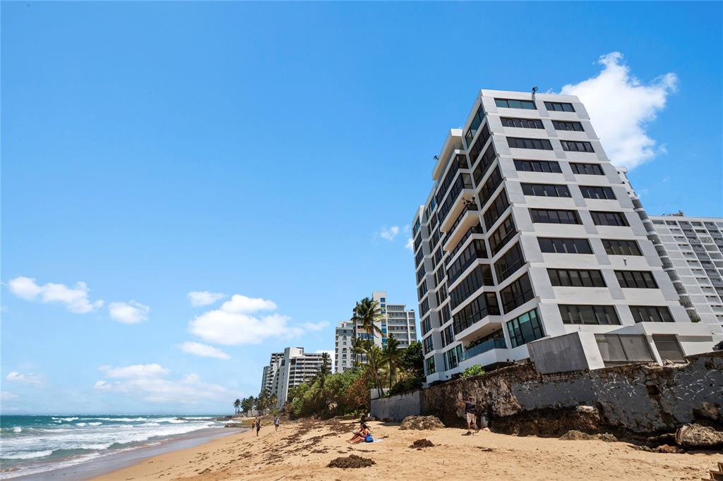 A tall white apartment building stands on a sandy beach next to the ocean — 1 CERVANTES STREET UNIT 5, SAN JUAN, PR