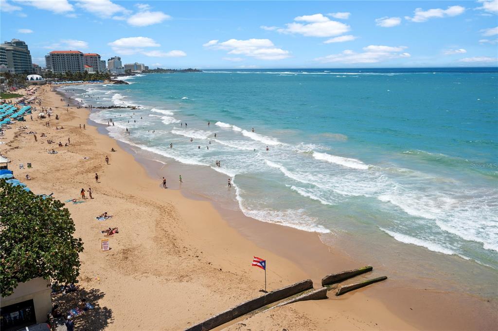 An elevated view of a sandy beach with ocean waves, people, and coastal buildings — 1 CERVANTES STREET UNIT 5, SAN JUAN, PR