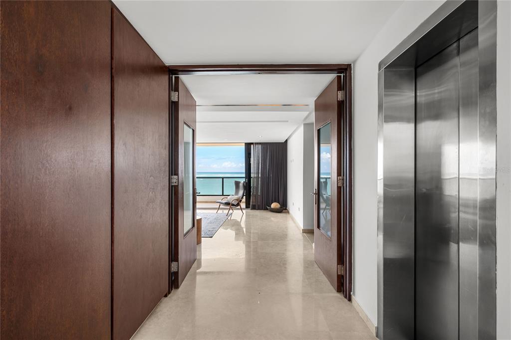 A hallway with a stainless steel elevator leads toward a room with ocean views — 1 CERVANTES STREET UNIT 5, SAN JUAN, PR