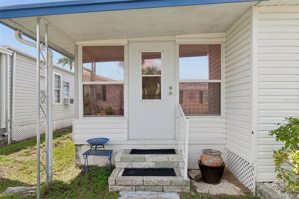 A white front door with a small window is centered between two large screened windows — 18675 US HIGHWAY 19 N UNIT 116, CLEARWATER, FL