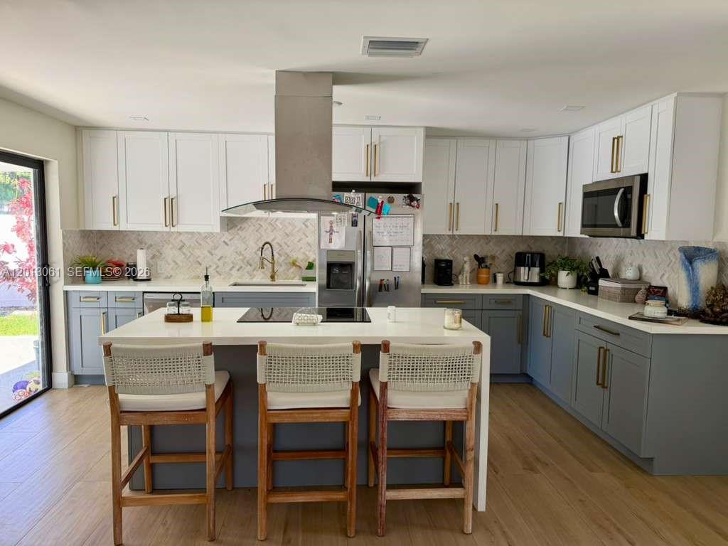 A modern kitchen features white upper cabinets, gray lower cabinets, and a central island — 151 SE 6th Ct, Pompano Beach FL 33060, POMPANO BEACH, FL