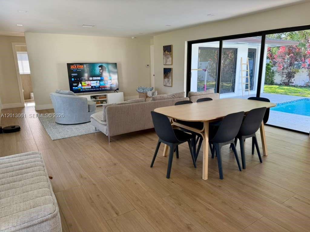 An open-concept living and dining area features light wood flooring and sliding glass doors — 151 SE 6th Ct, Pompano Beach FL 33060, POMPANO BEACH, FL