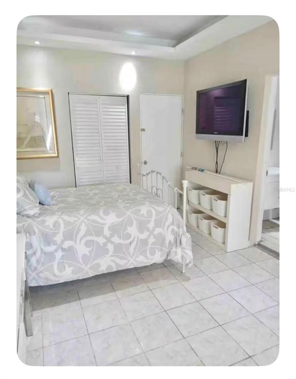 A bedroom with a bed, a wall-mounted television, storage shelving, and tiled flooring — 274 CALLE PINTA UNIT 1A, SAN JUAN, PR