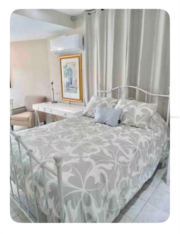 A bedroom features a white metal bed frame, patterned bedding, a desk, and a wall-mounted air conditioner — 274 CALLE PINTA UNIT 1A, SAN JUAN, PR