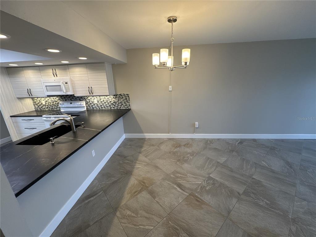 A kitchen with light cabinets and dark countertops opens to a dining area with tile — 3600 BAL HARBOR BOULEVARD UNIT 1G, PUNTA GORDA, FL
