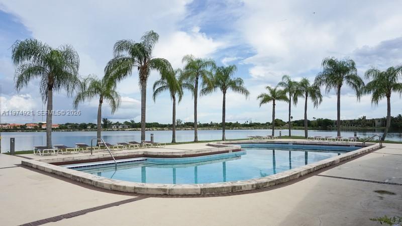 A swimming pool sits on a patio lined with palm trees overlooking a lake — 331 Ives Dairy Rd # 10, Miami FL 33179, MIAMI, FL
