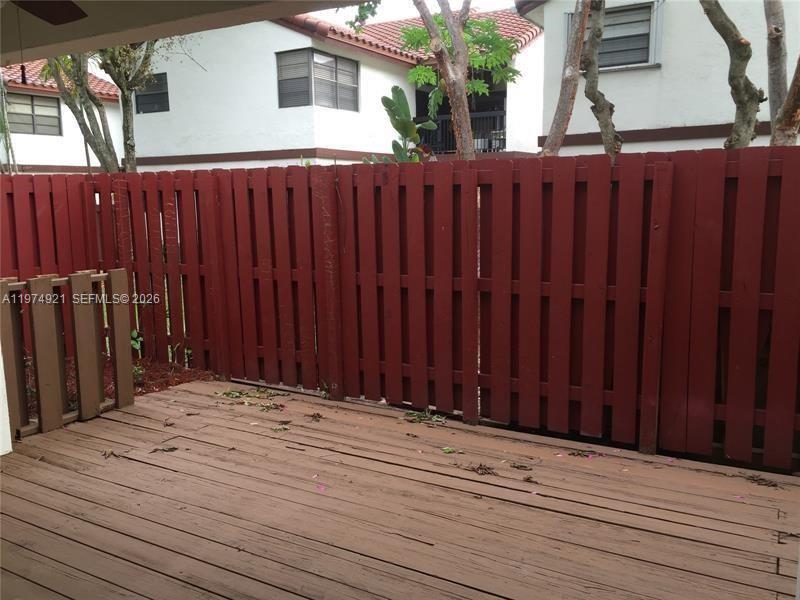 A wooden deck features a red privacy fence in front of a multi-story building — 331 Ives Dairy Rd # 10, Miami FL 33179, MIAMI, FL